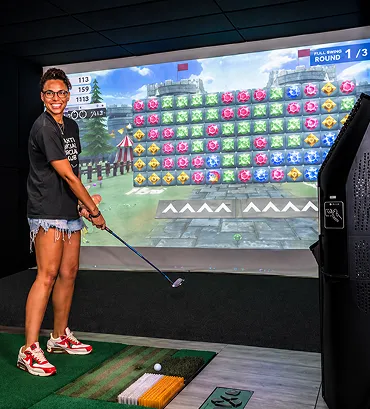 A golfer practicing in front of a TeedUp simulator screen