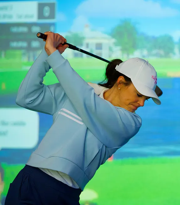 Golfer swinging inside a Teed Up simulator bay